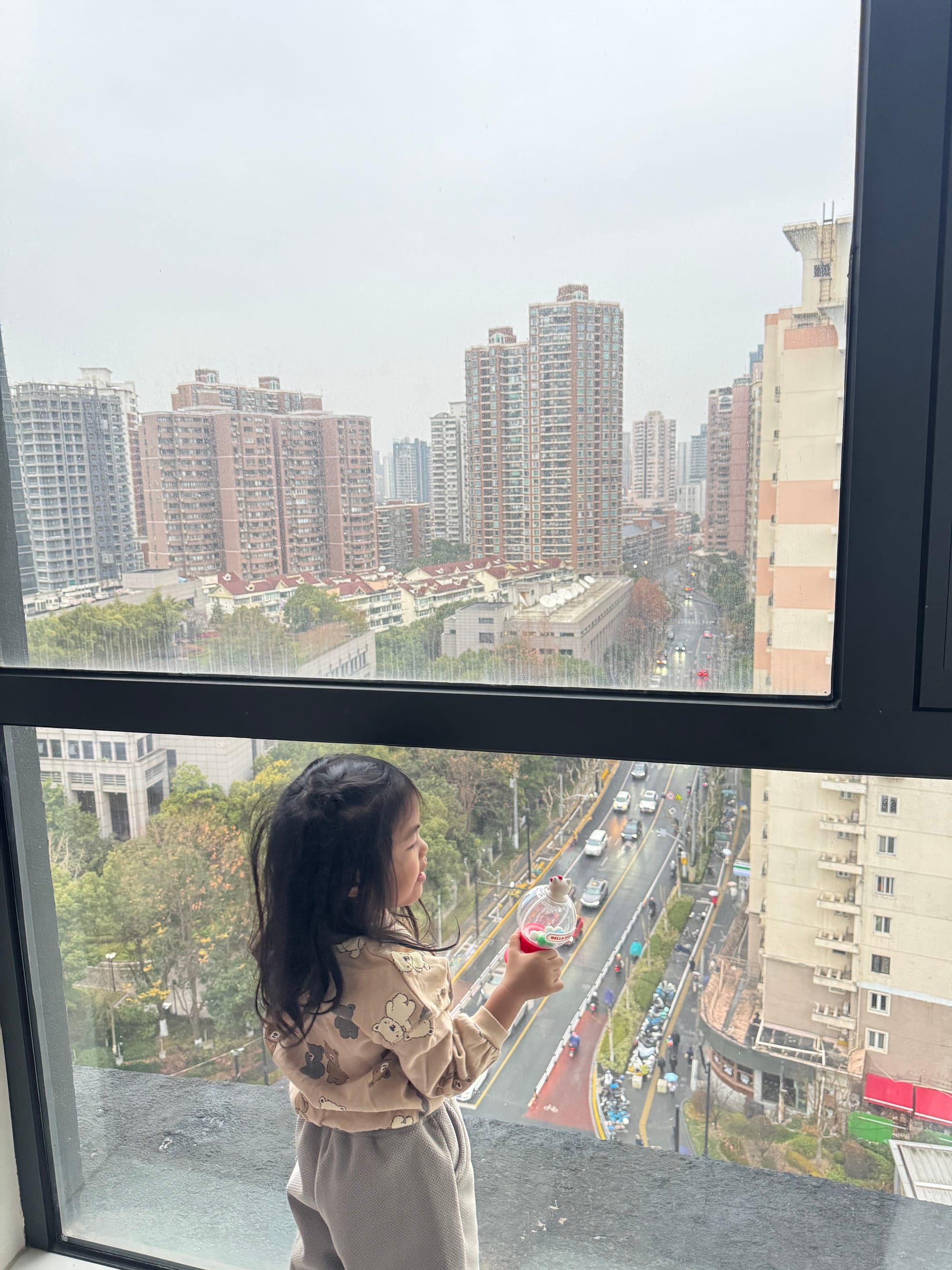 Kid looking out the window of a hotel room in Shanghai