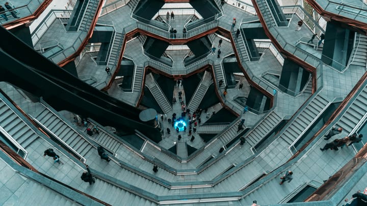 People walking on a complex system of gray and white concrete staircases and bridges