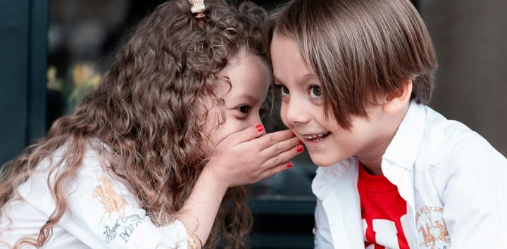 Children whispering. Photo by Saeed Karimi from Unsplash.com.