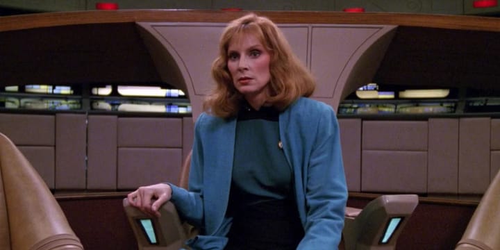 A screen capture of Star Trek: The Next Generaion season 4, episode 5, "Remember Me" showing Dr. Beverly Crusher in the captain's seat of the starship Enterprise